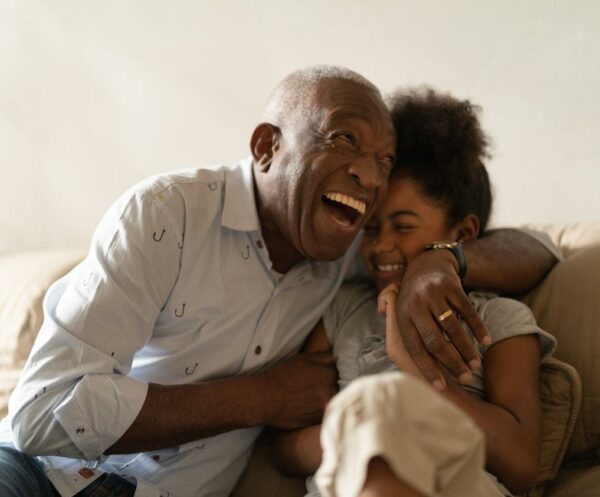 grandad playing with granddaughter and laughing at home